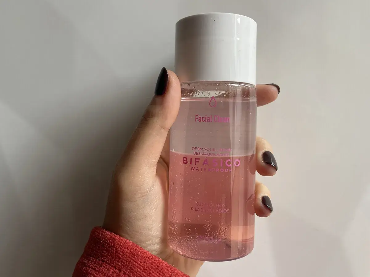 Mano sujetando un agua micelar rosa Bifásico de Mercadona, ideal para desmaquillar ojos y labios.