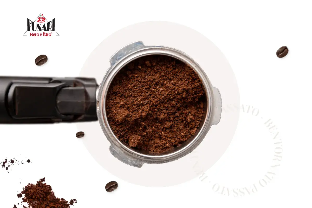 Macinatura caffè fine nel portafiltro, pronta per un espresso perfetto. Chicchi sparsi e logo Fusari.