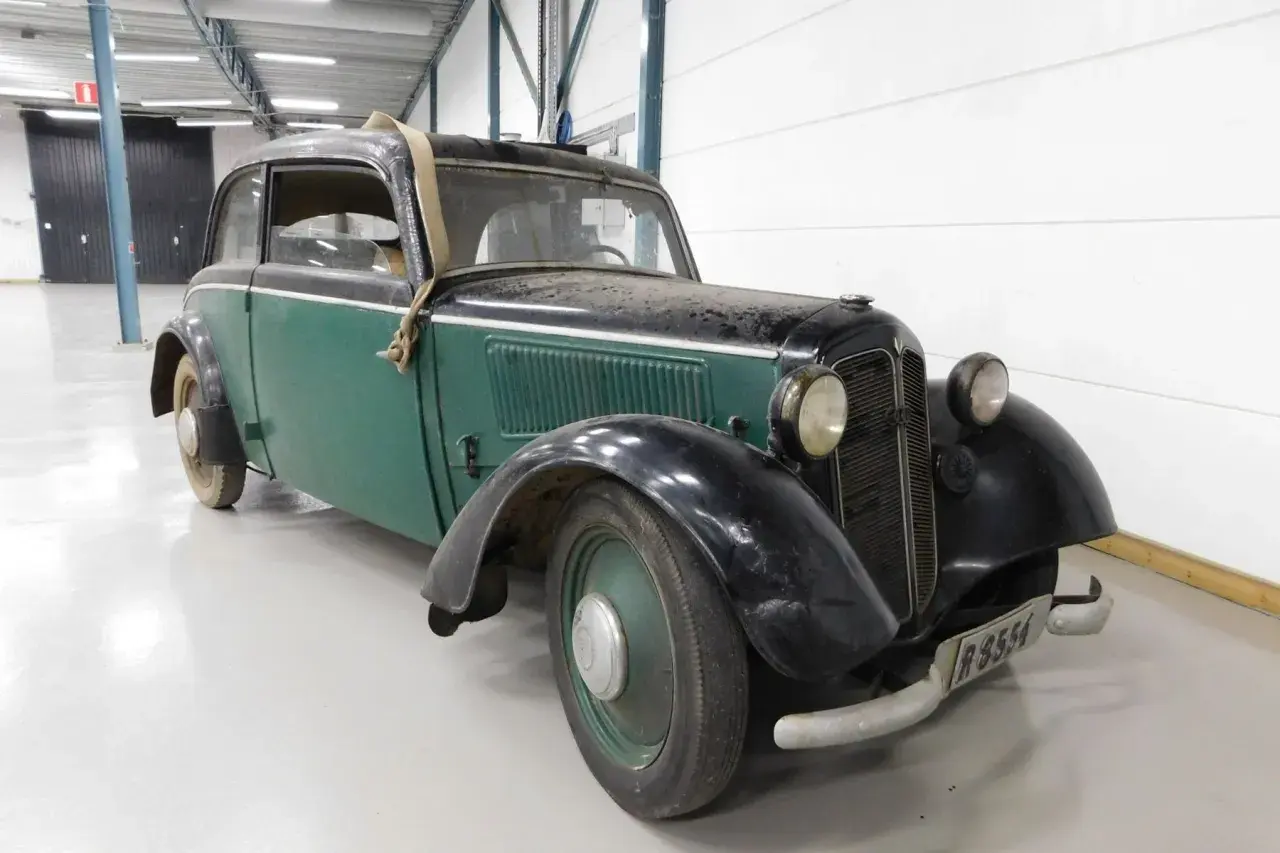 En grön och svart DKW med en spånkorgsdetalj på taket, står i ett garage.