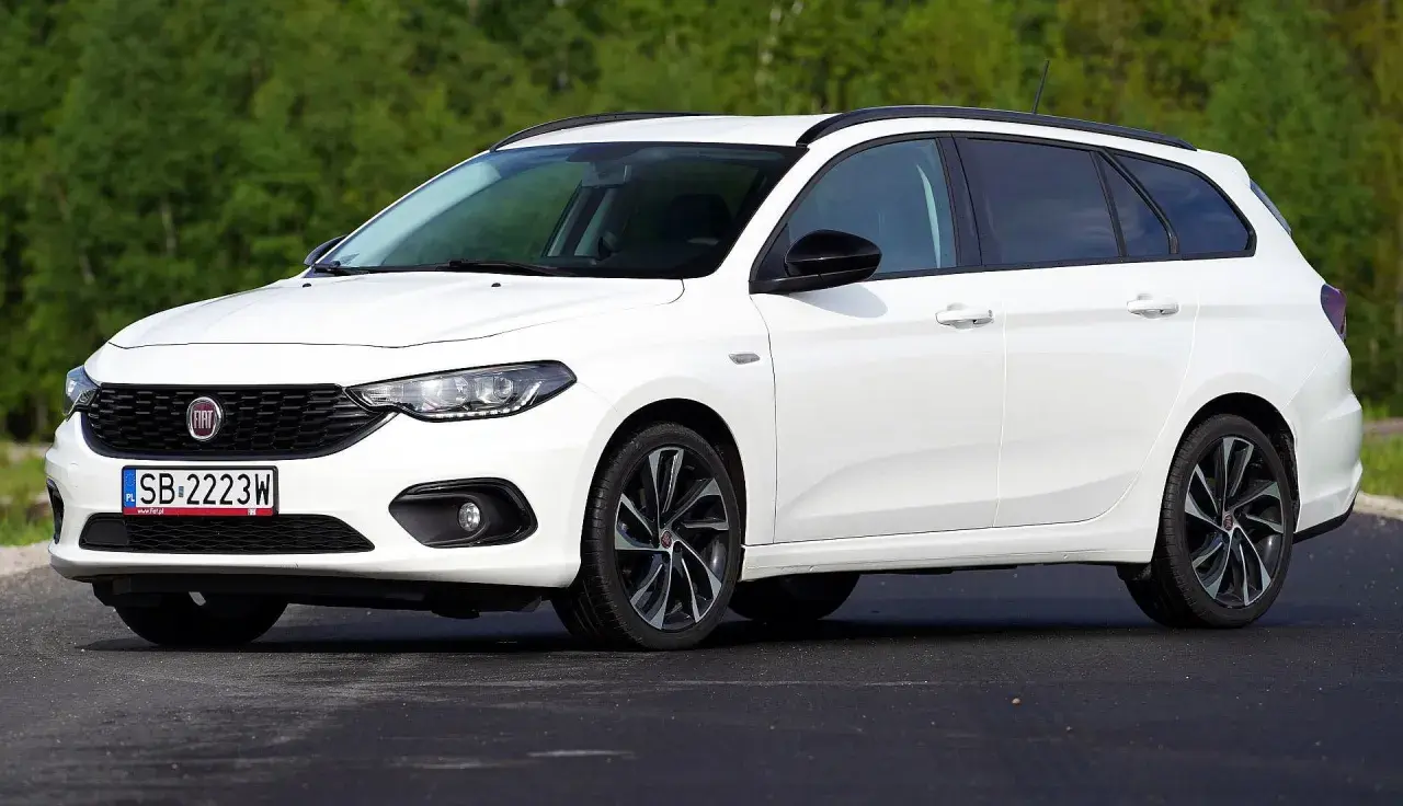 Biały Fiat Tipo kombi na tle zieleni. Wiele osób szuka takich aut, sprawdzając fiat tipo opinie.
