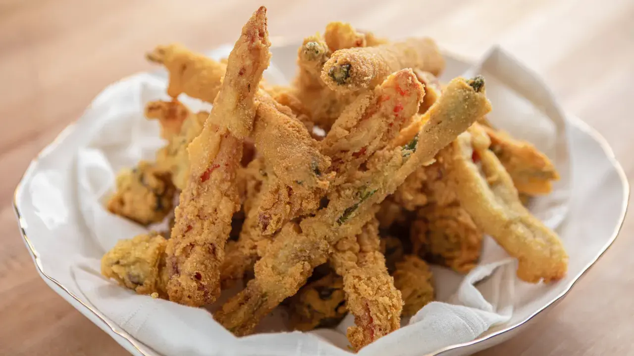 Crispy, golden-brown vegetable sticks coated in a light, airy gluten free tempura batter, served in a white bowl lined with a napkin.