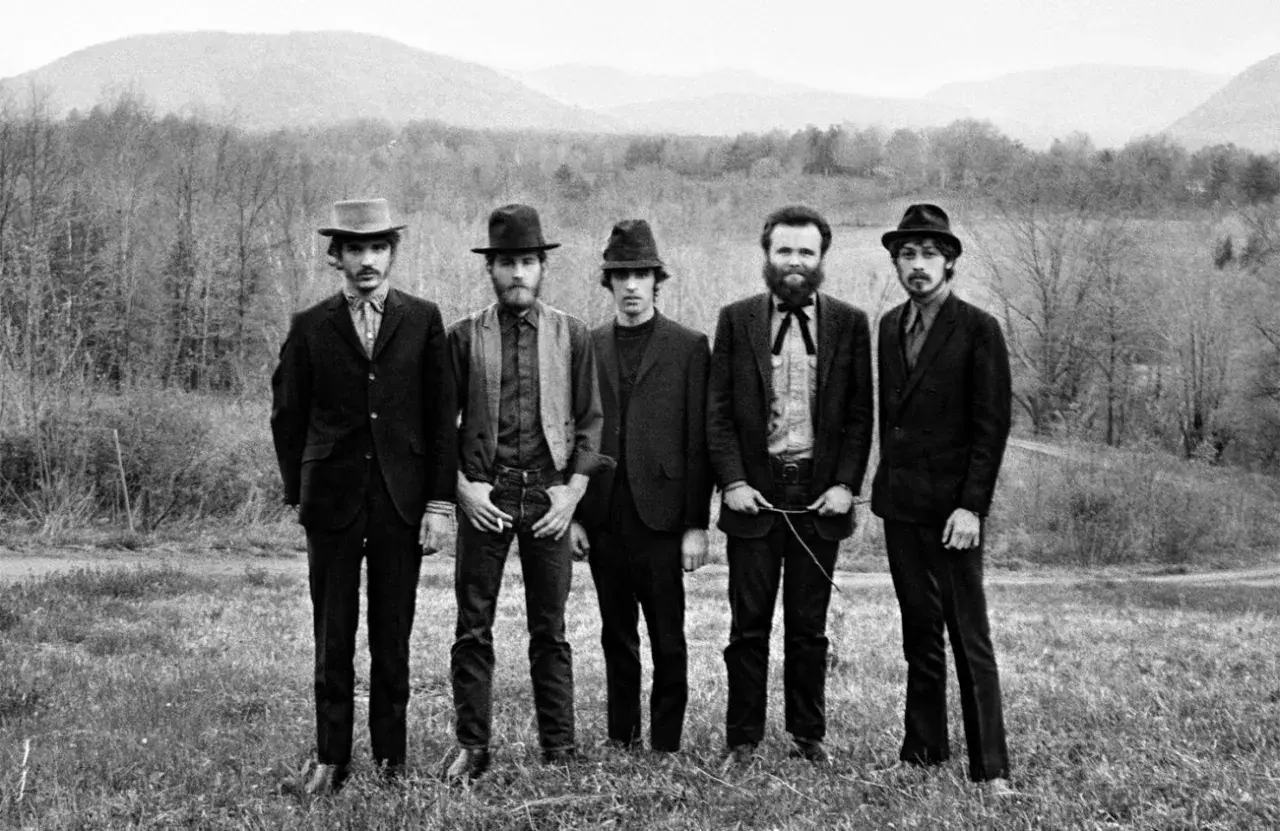 The Band, who wrote "The Weight," pose in a field with mountains in the background.