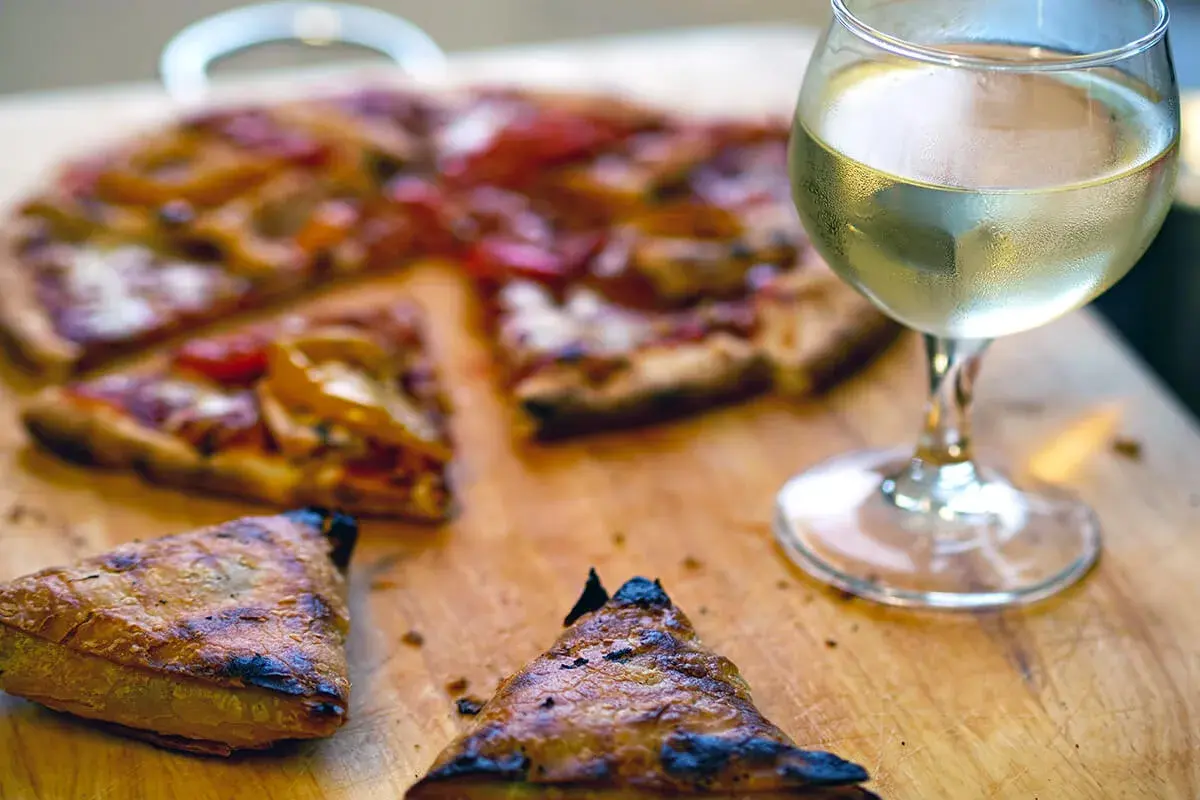 En saftig pizza med ett glas vitt vin till. Perfekt för en mysig kväll.