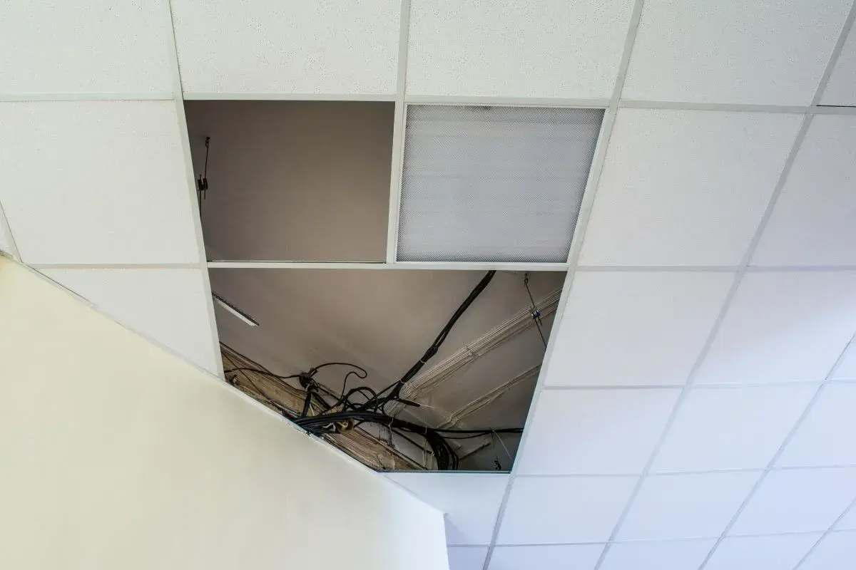 Schema distanza montanti controsoffitto cartongesso: cavi elettrici a vista in un'apertura del controsoffitto modulare.