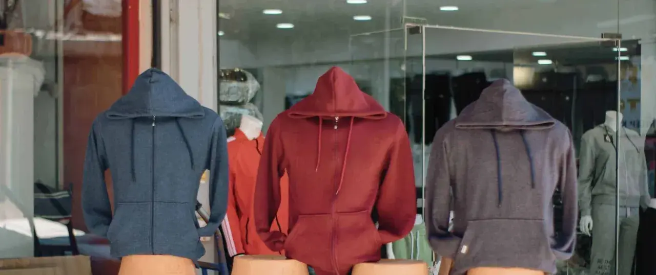 Drei Hoodies in Blau, Rot und Grau. Ein Sweatshirt ist ein bequemes Kleidungsstück mit Kapuze.
