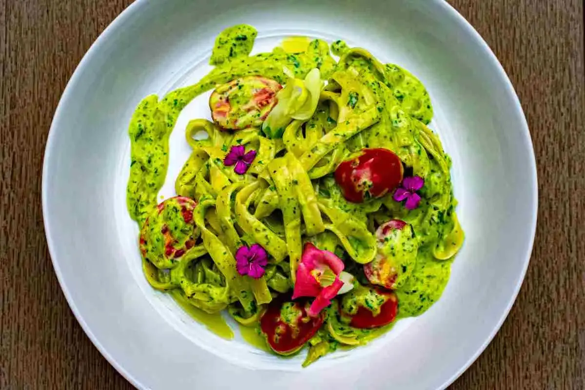 Tagliatelle fresche condite con un cremoso pesto di zucchine, pomodorini e fiori eduli.