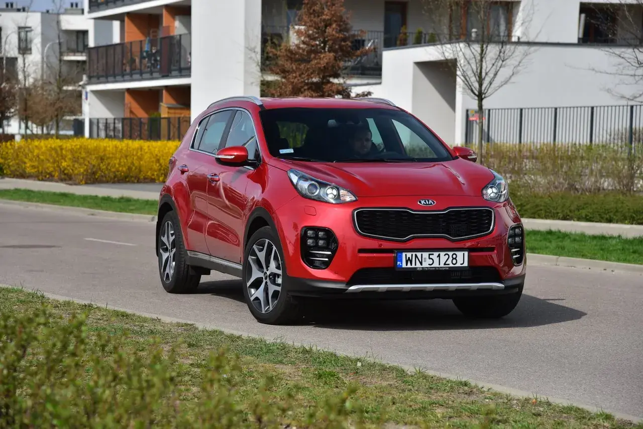 Czerwony Kia Sportage 4 na drodze, gotowy do wymiany żarówki.