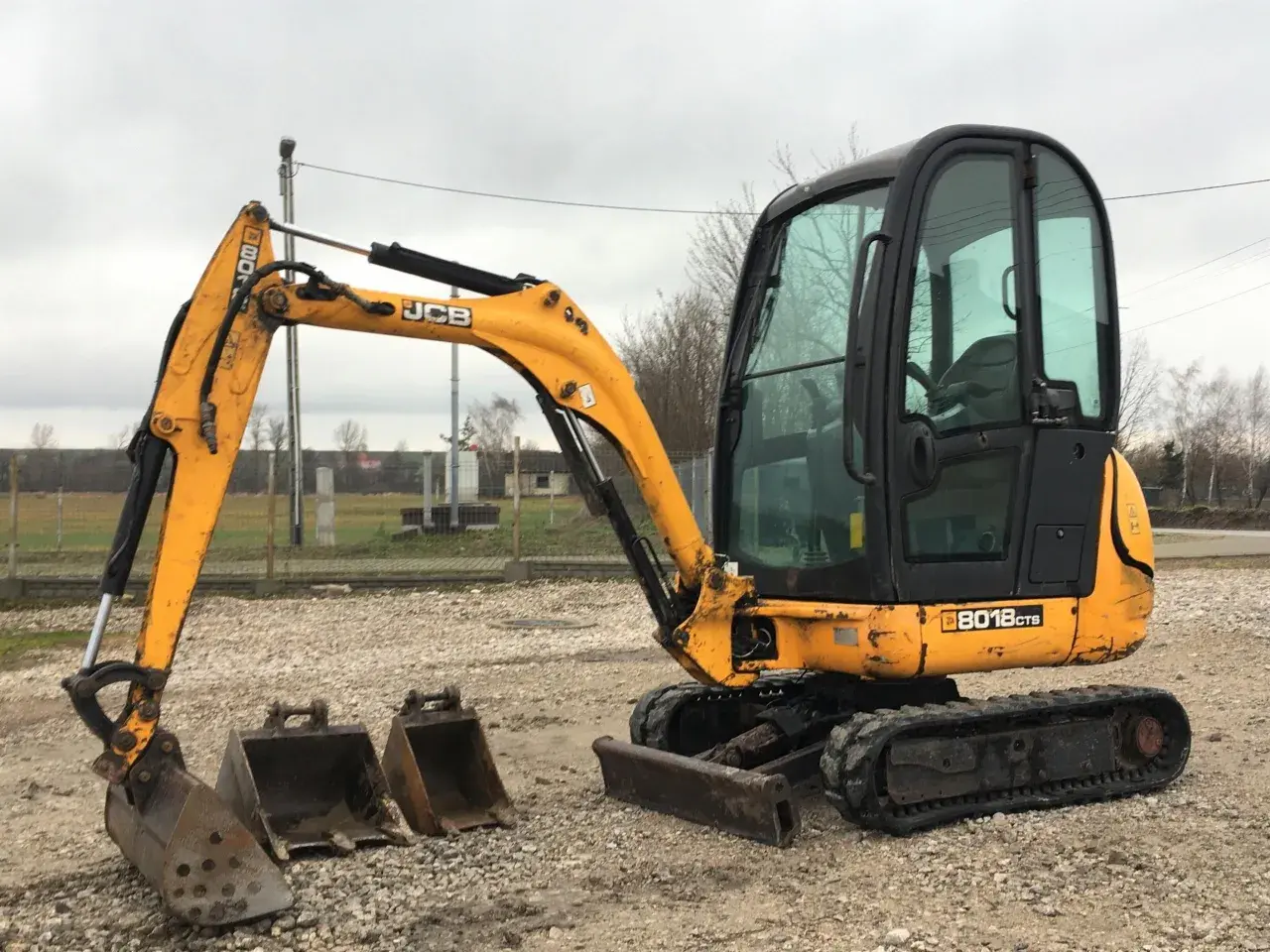 Żółta koparka gąsienicowa JCB 8018CTS z kabiną i dwoma łyżkami. Idealna do prac budowlanych, poznaj jej dane techniczne.