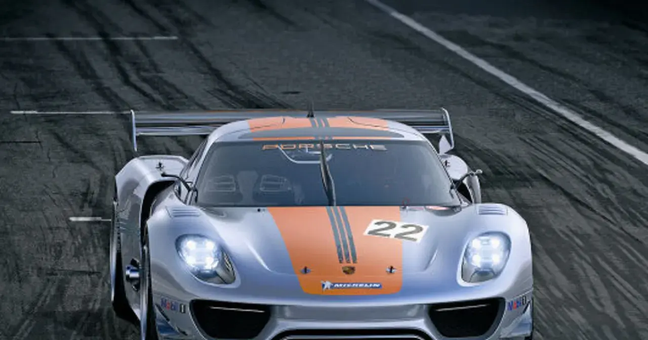 Srebrny Porsche 918 Spyder z pomarańczowymi pasami i numerem 22 na masce pędzi po torze wyścigowym.