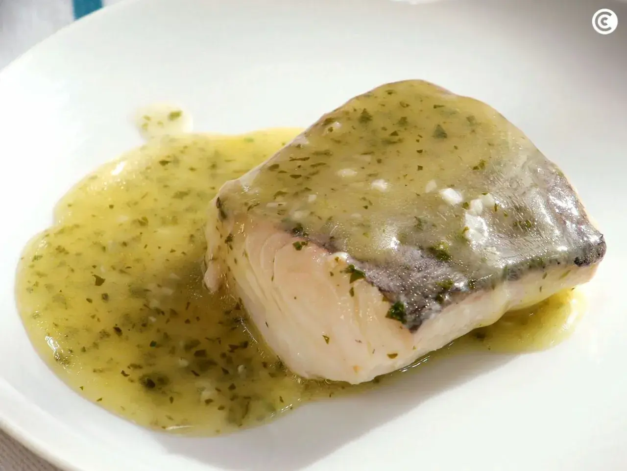Filete de pescado blanco bañado en una sabrosa salsa verde, con hierbas picadas y un toque de ajo.