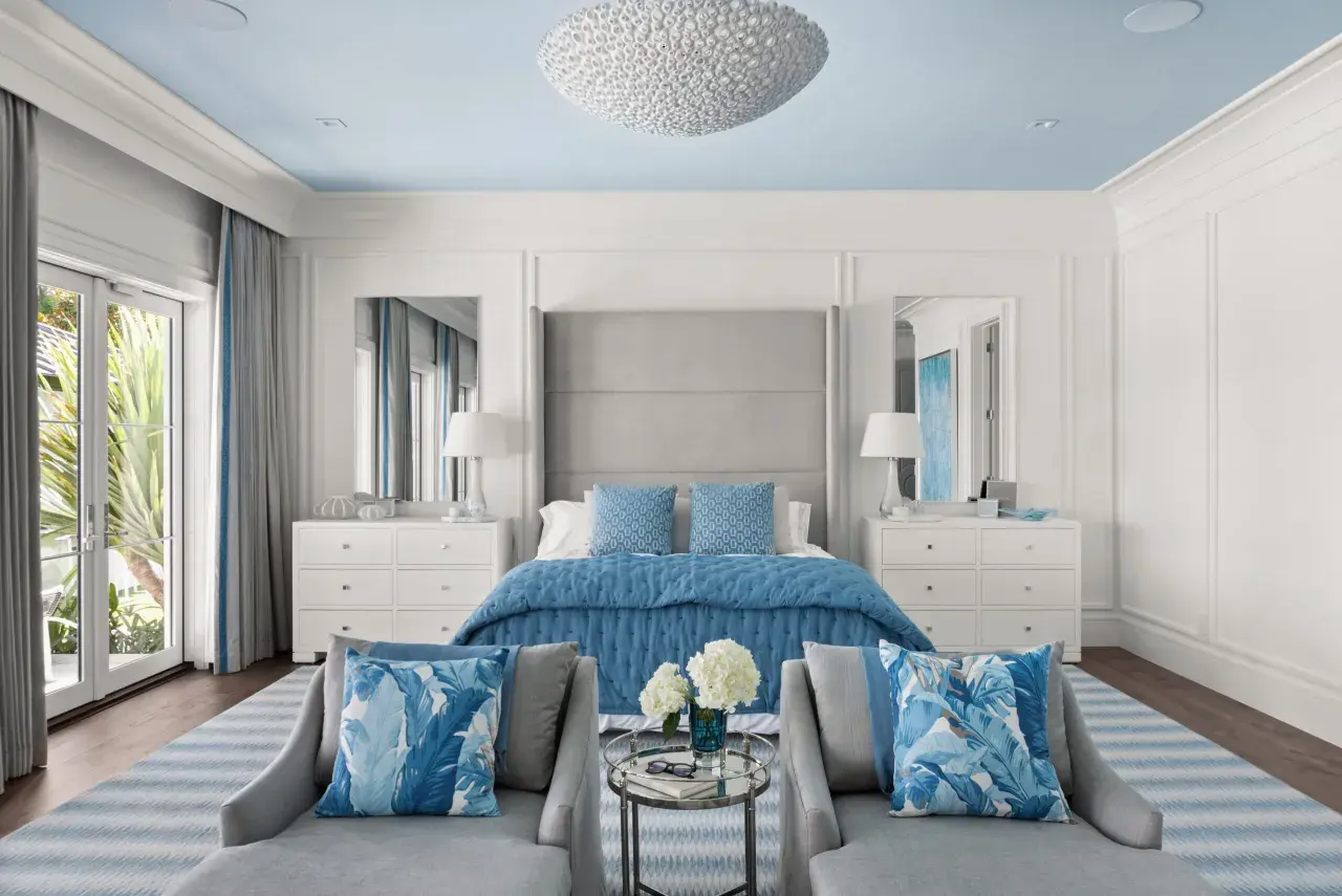 Serene master bedroom layout ideas with a blue and white palette, featuring a plush bed, mirrored nightstands, and comfortable seating.