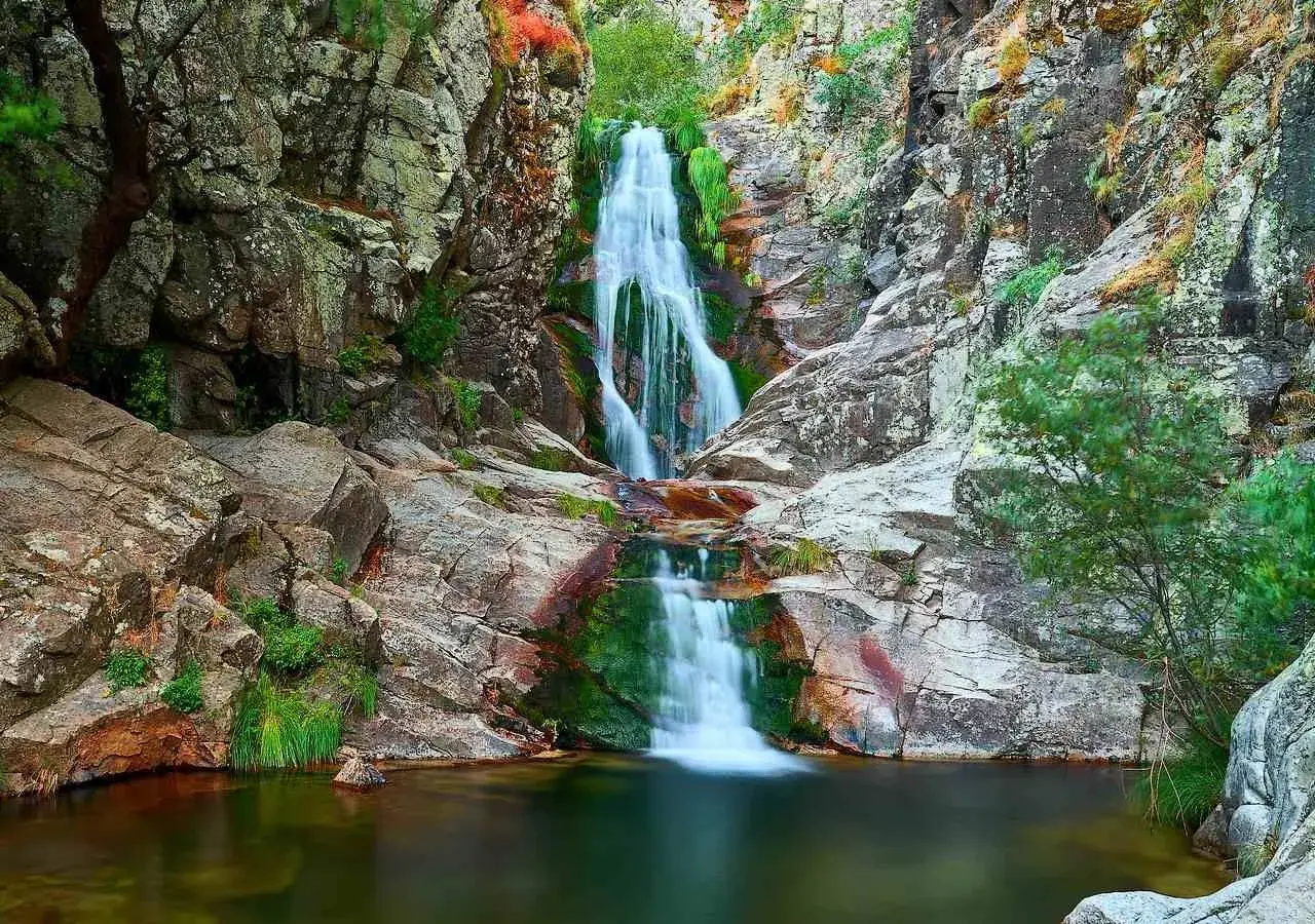Cascada del Purgatorio, una joya natural en la ruta. Agua cayendo entre rocas y vegetación exuberante.