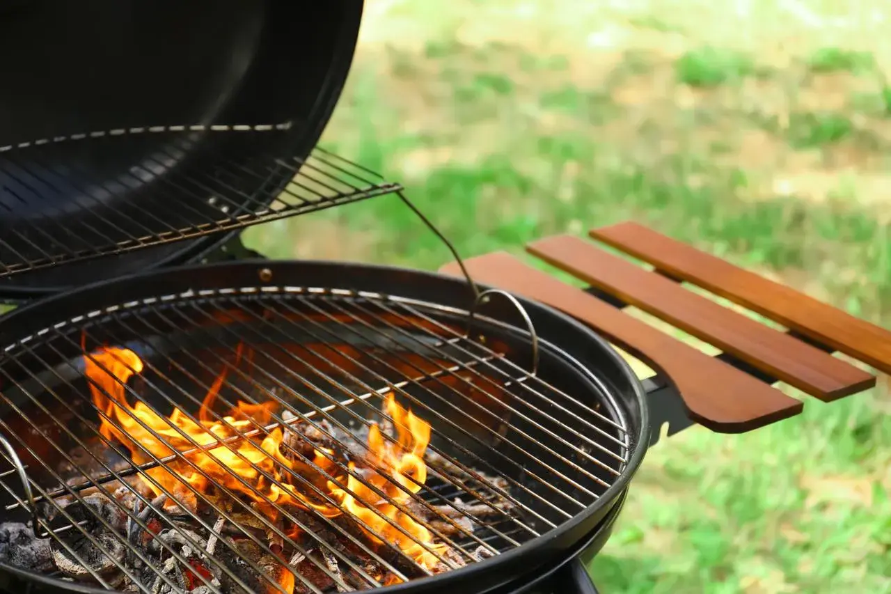 Un barbecue prêt à l'emploi, les flammes montent, signalant la bonne température bbq pour un repas en plein air.