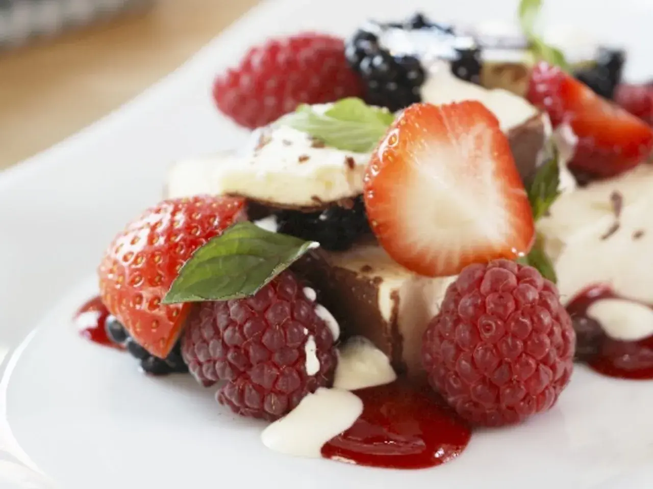 Ein köstlicher geeister Kaiserschmarrn mit frischen Beeren, Erdbeeren und Himbeeren, garniert mit Minze und einer cremigen Sauce.