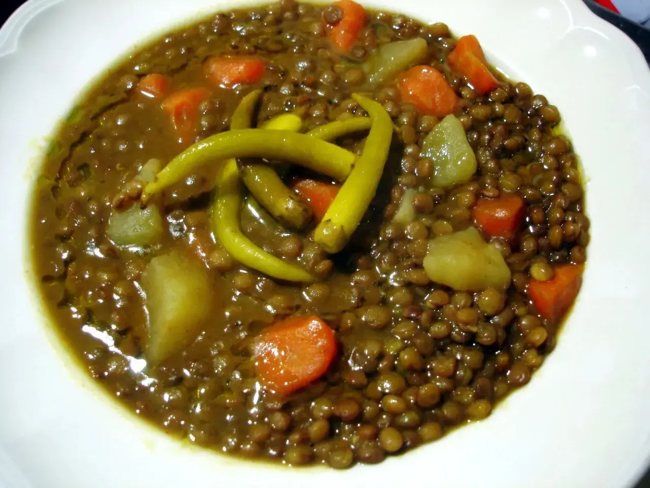 Un plato de lentejas con verduras, patatas y guindillas verdes. Un guiso reconfortante y nutritivo.