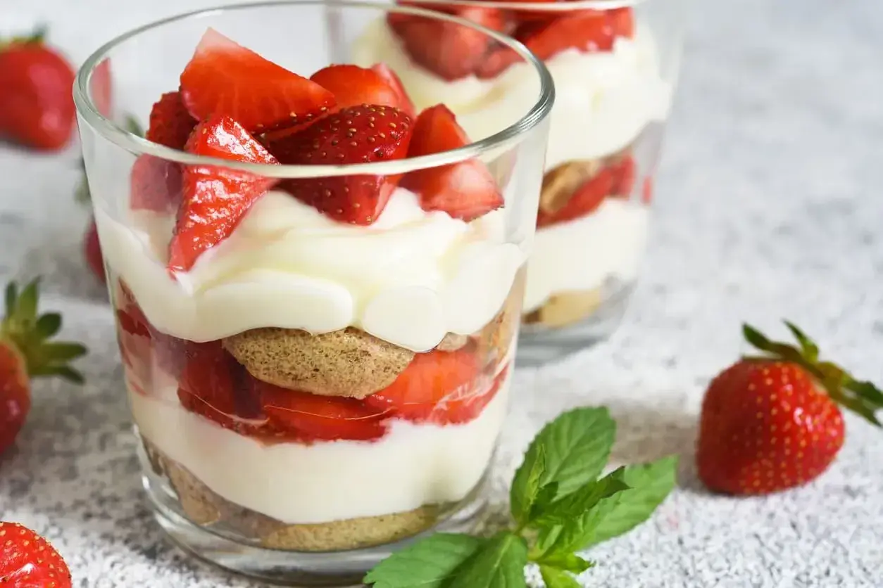 Un délicieux dessert léger aux fraises, alternant biscuits, crème onctueuse et fruits rouges frais, servi dans des verres.
