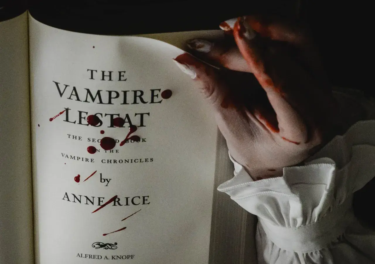 Książki o wampirach dla młodzieży, jak "Wampir Lestat" Anne Rice, z krwawymi śladami na stronach i dłoni.
