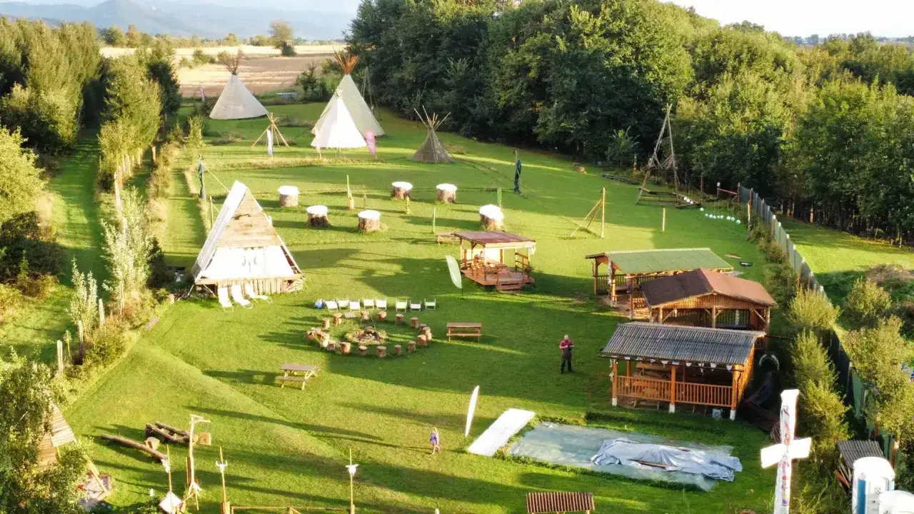Wioska indiańska w Lubelskiem z tipi, drewnianymi chatkami i miejscem na ognisko.