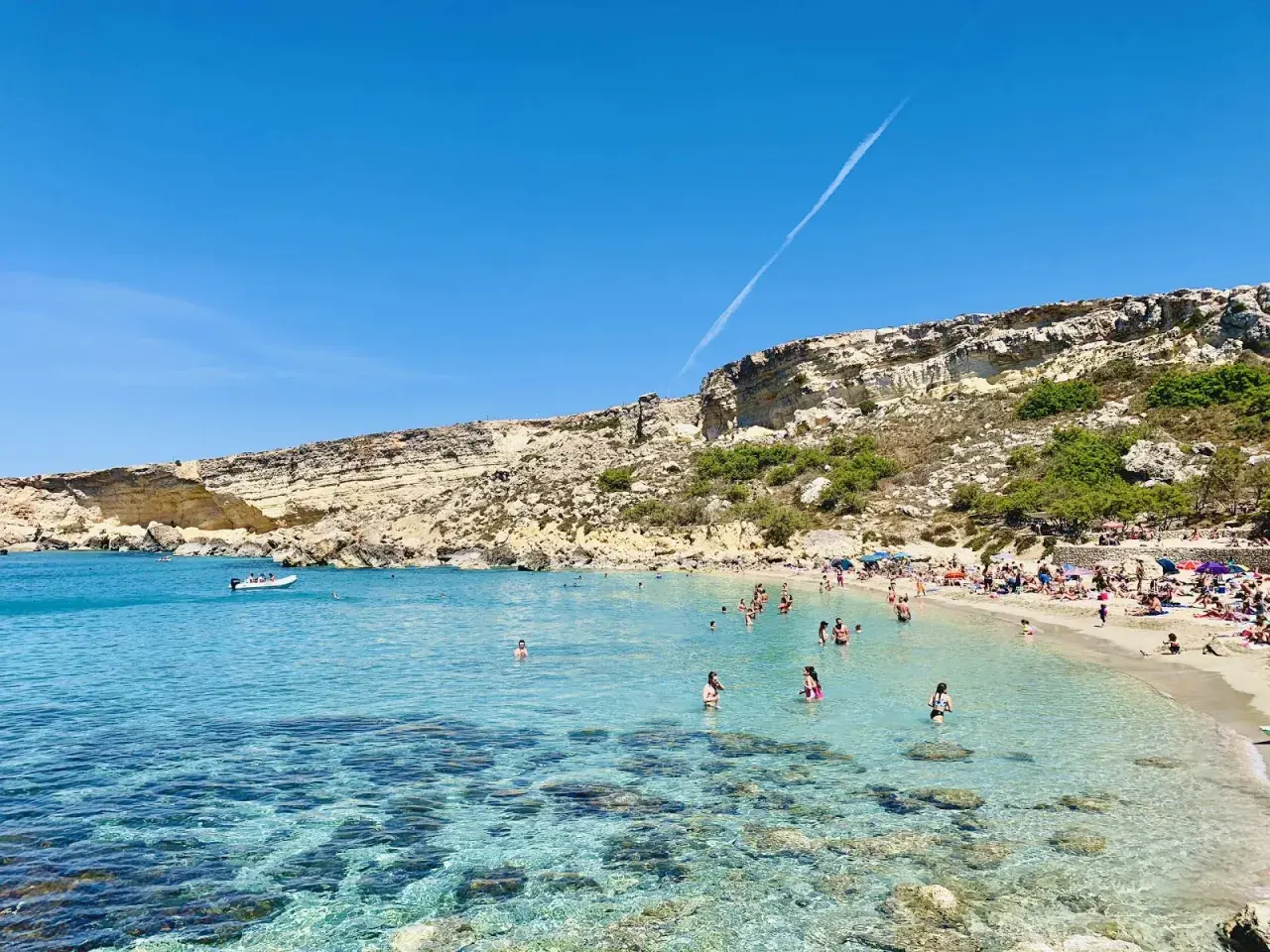 Słoneczny dzień w Paradise Bay na Malcie. Turkusowa woda, piaszczysta plaża i skaliste klify tworzą idylliczny krajobraz.