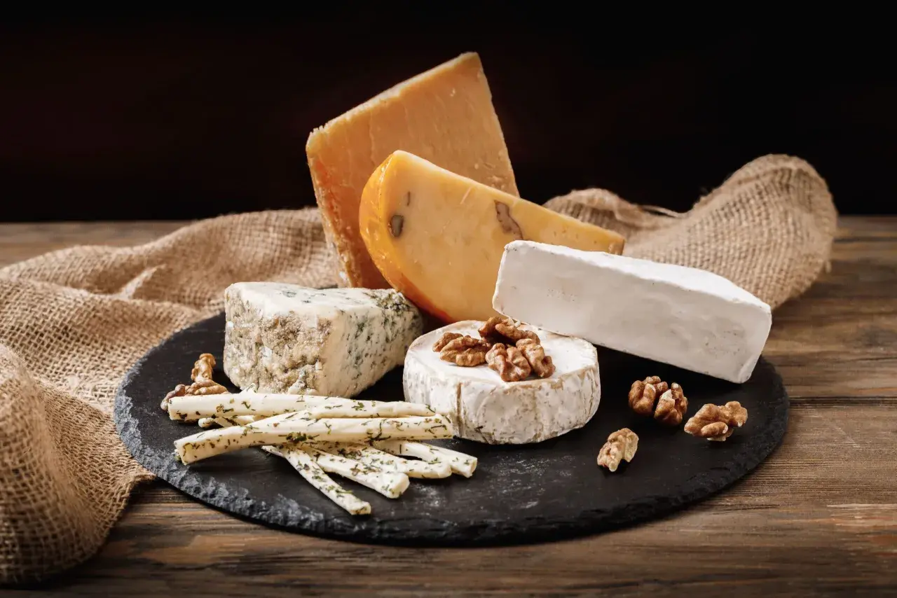 Selezione di formaggi su tagliere di ardesia: brie, erborinato, stagionato e grissini alle erbe. Un'idea per una dieta equilibrata e gustosa.