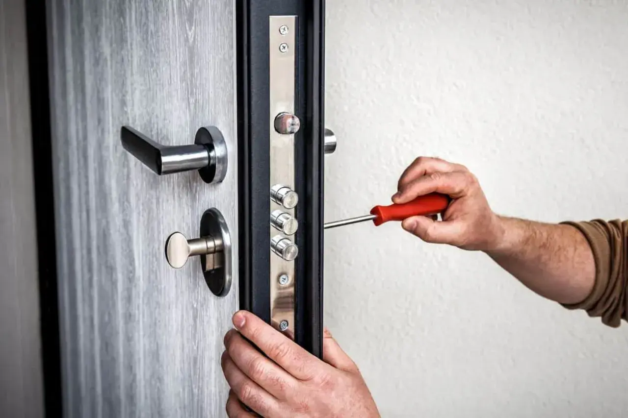 Maintenant, on ajuste le pêne porte avec un tournevis. La serrure de sécurité est en cours d'installation sur la porte grise.