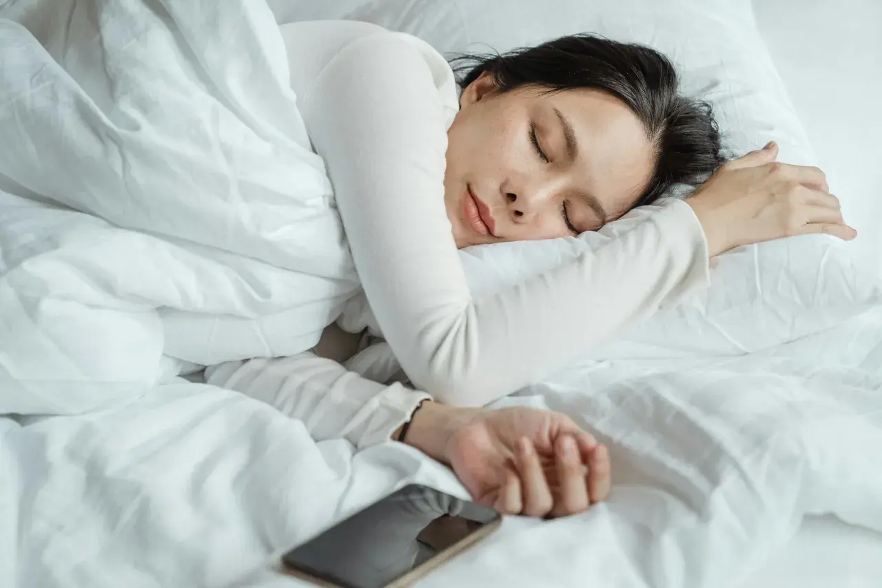 A woman sleeps peacefully, perhaps a natural short sleeper, with her phone nearby.
