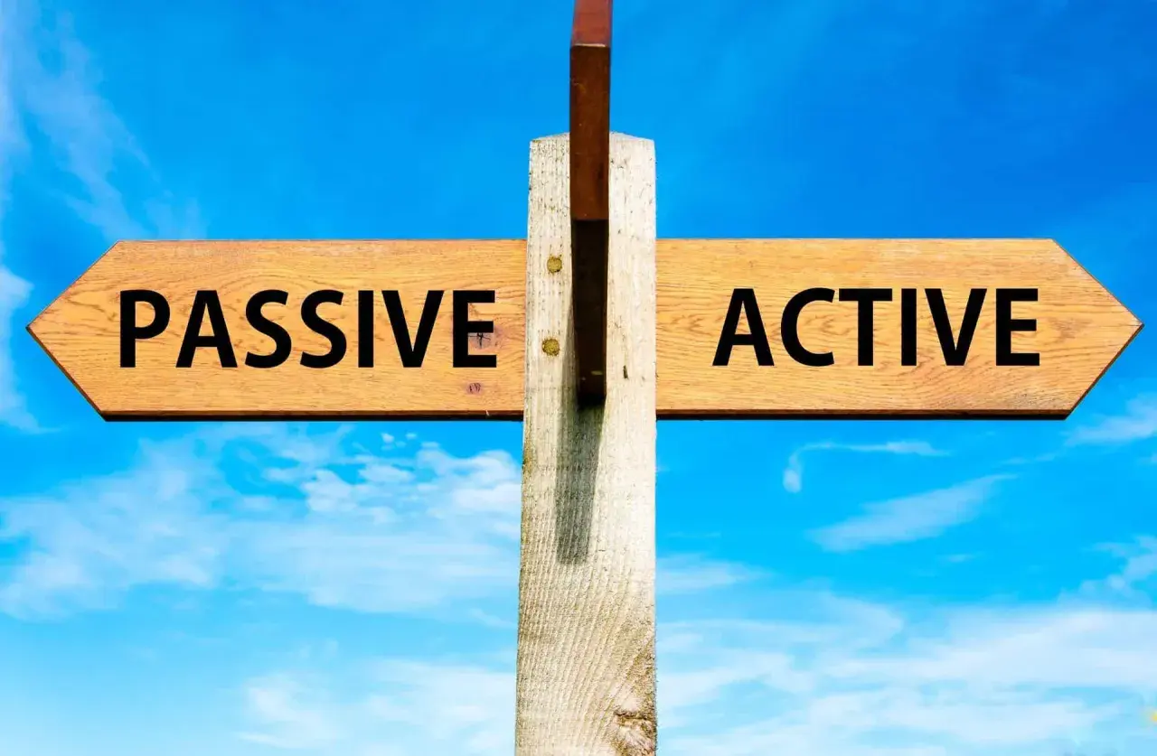 Cartello stradale con frecce "PASSIVE" e "ACTIVE" sotto un cielo azzurro. La scelta tra essere passivi o attivi è presentata.