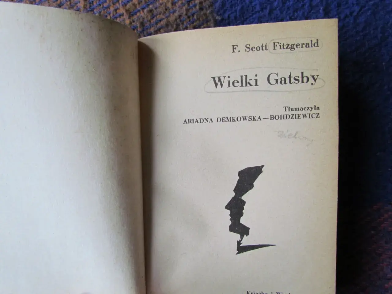 Strona tytułowa "Wielkiego Gatsby'ego" F. Scotta Fitzgeralda. Czarno-biała grafika profilu twarzy.