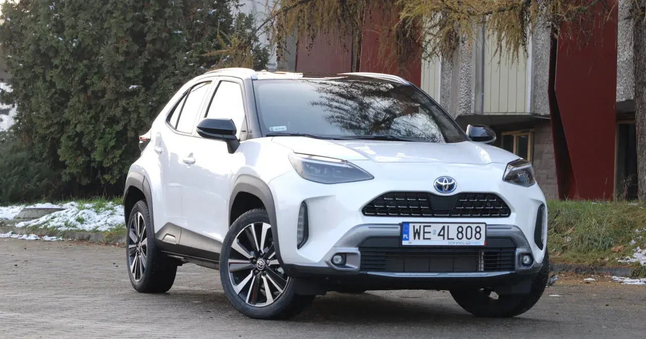 Biały Toyota Yaris Cross 2025 z czarnymi dodatkami, zaparkowany na zewnątrz.