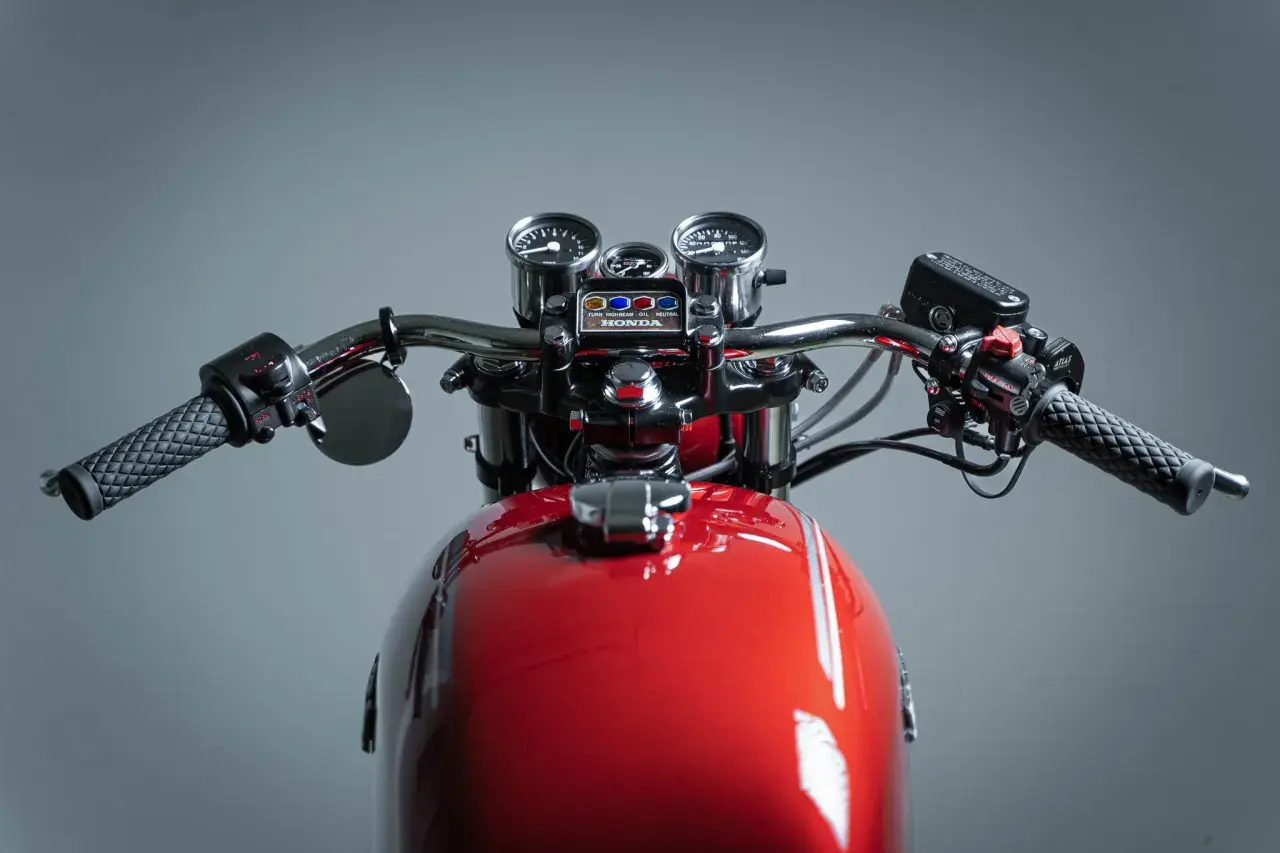 Manubrio di una moto custom rossa con specchietti, tachimetro e contagiri.