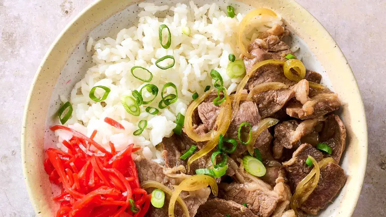 A delicious gyudon recipe featuring tender beef and onions over fluffy rice, garnished with pickled ginger and green onions.