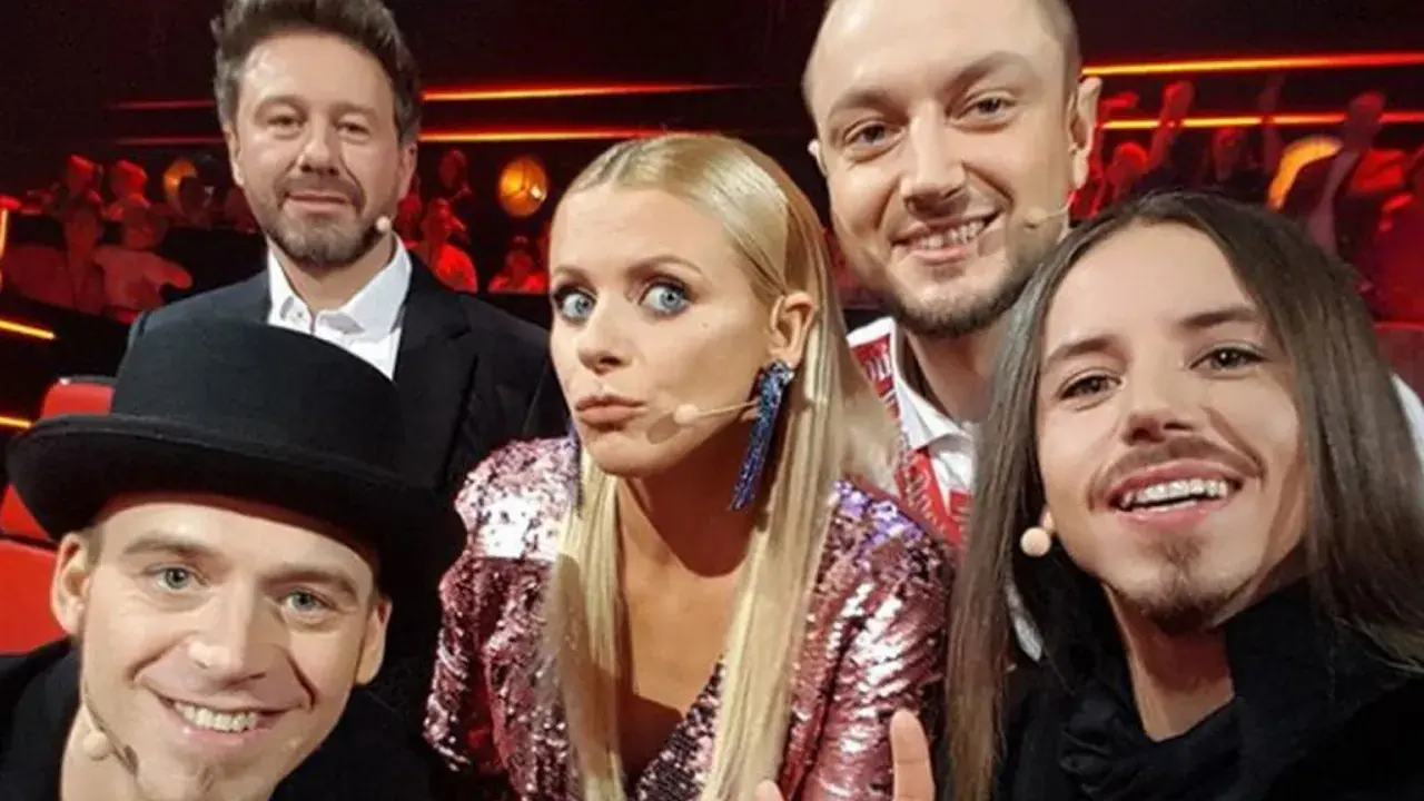 Uśmiechnięci jurorzy Voice of Poland w barwnych strojach, gotowi oceniać talenty.