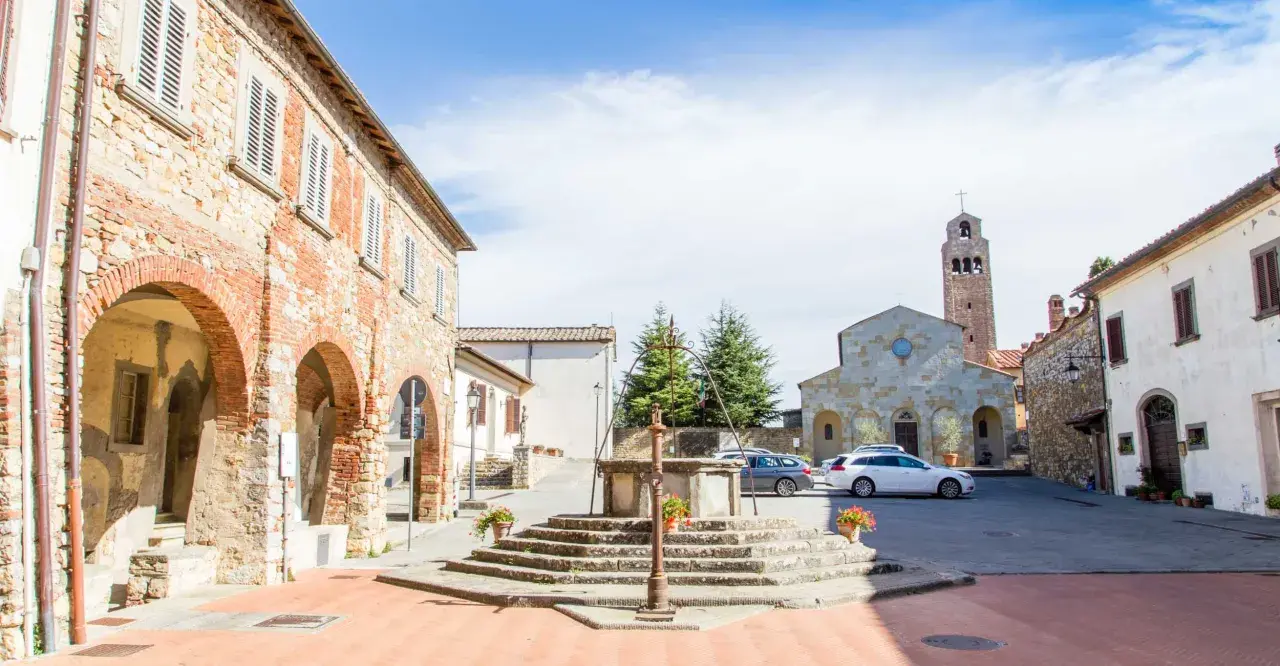 Piazza di Civitella Val di Chiana con pozzo antico, chiesa romanica e case in pietra.