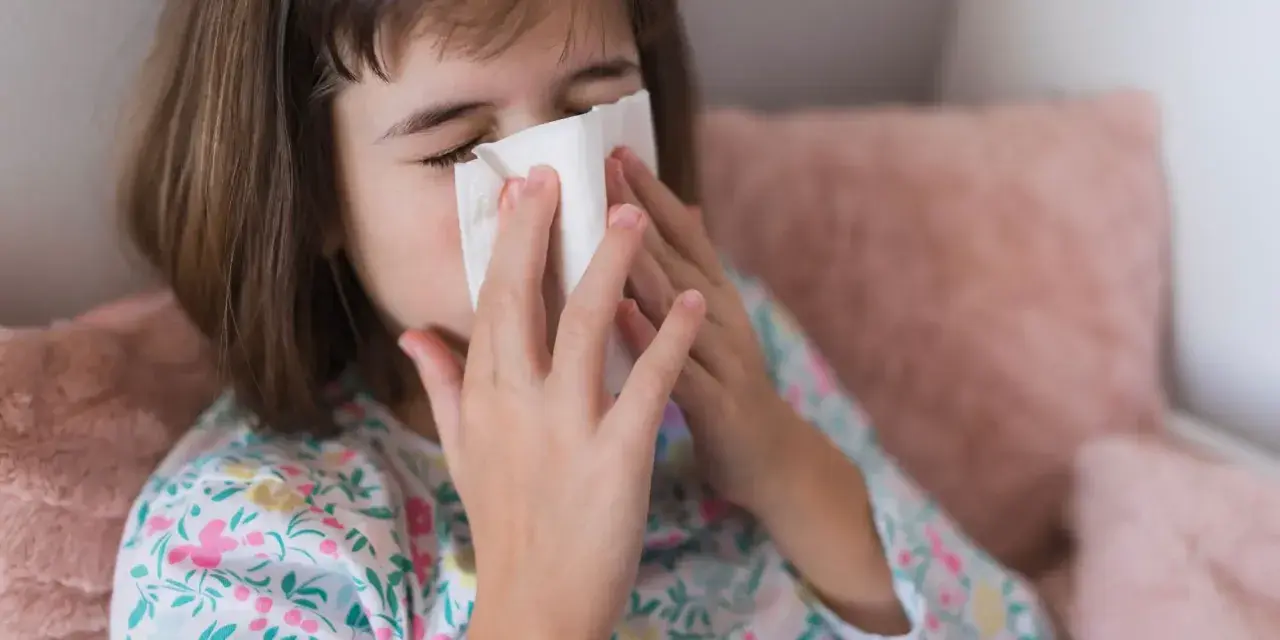 Dziewczynka z chusteczką przy nosie, być może potrzebuje antybiotyku na zatoki.