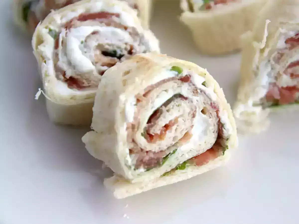 Rouleaux de pain de mie garnis de fromage frais et de jambon, coupés en tronçons pour un apéritif gourmand.