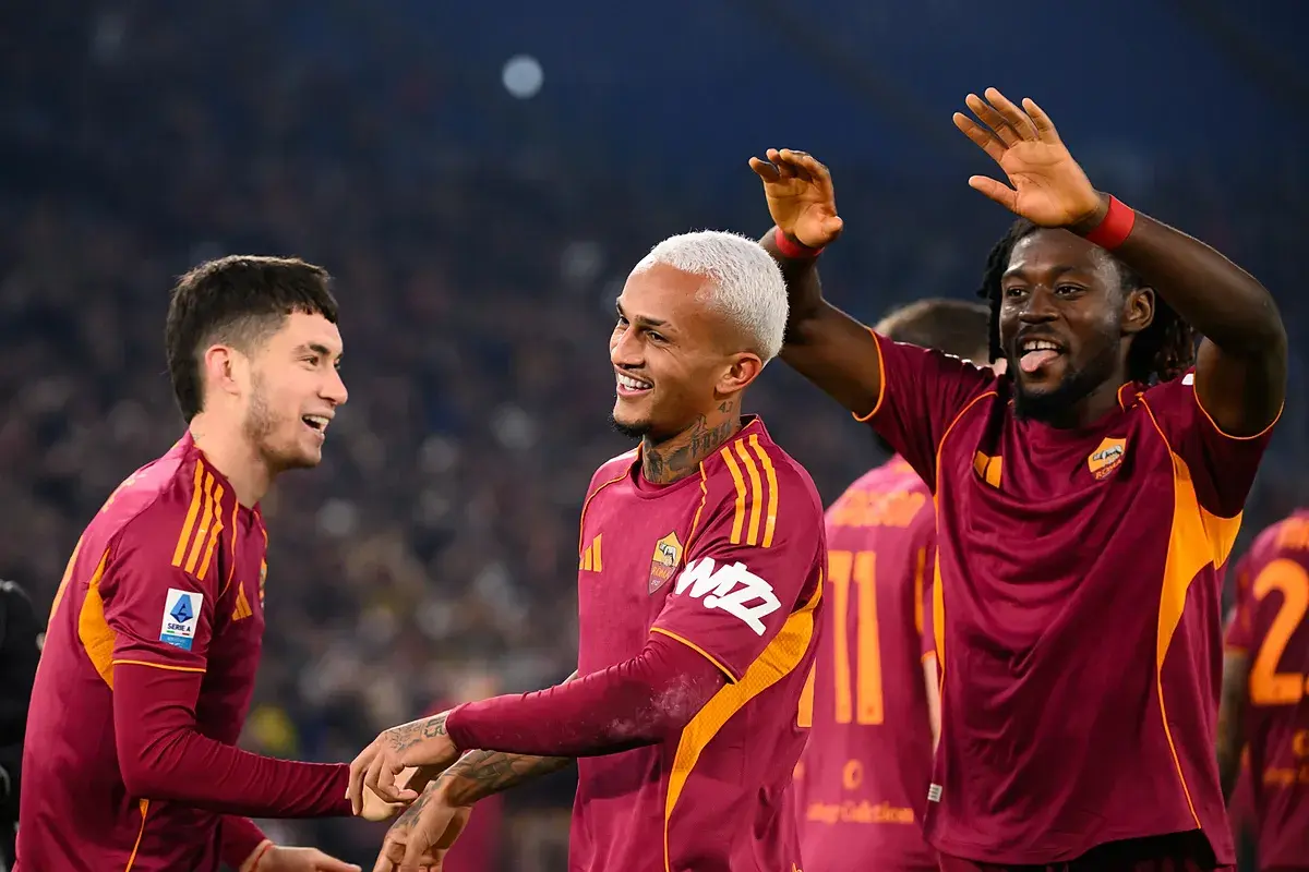 Piłkarze AS Roma świętują zwycięstwo nad Genoą CFC. Radość na twarzach zawodników, jeden z nich podnosi ręce w geście triumfu.