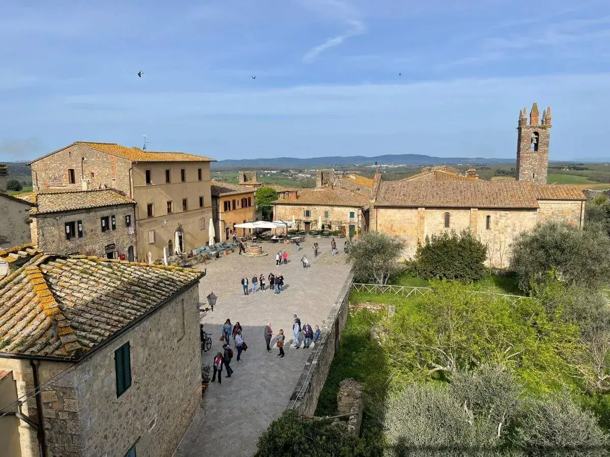 Piazza di Monteriggioni, un borgo medievale con case in pietra e un campanile. Ecco cosa vedere: un luogo incantevole da esplorare.