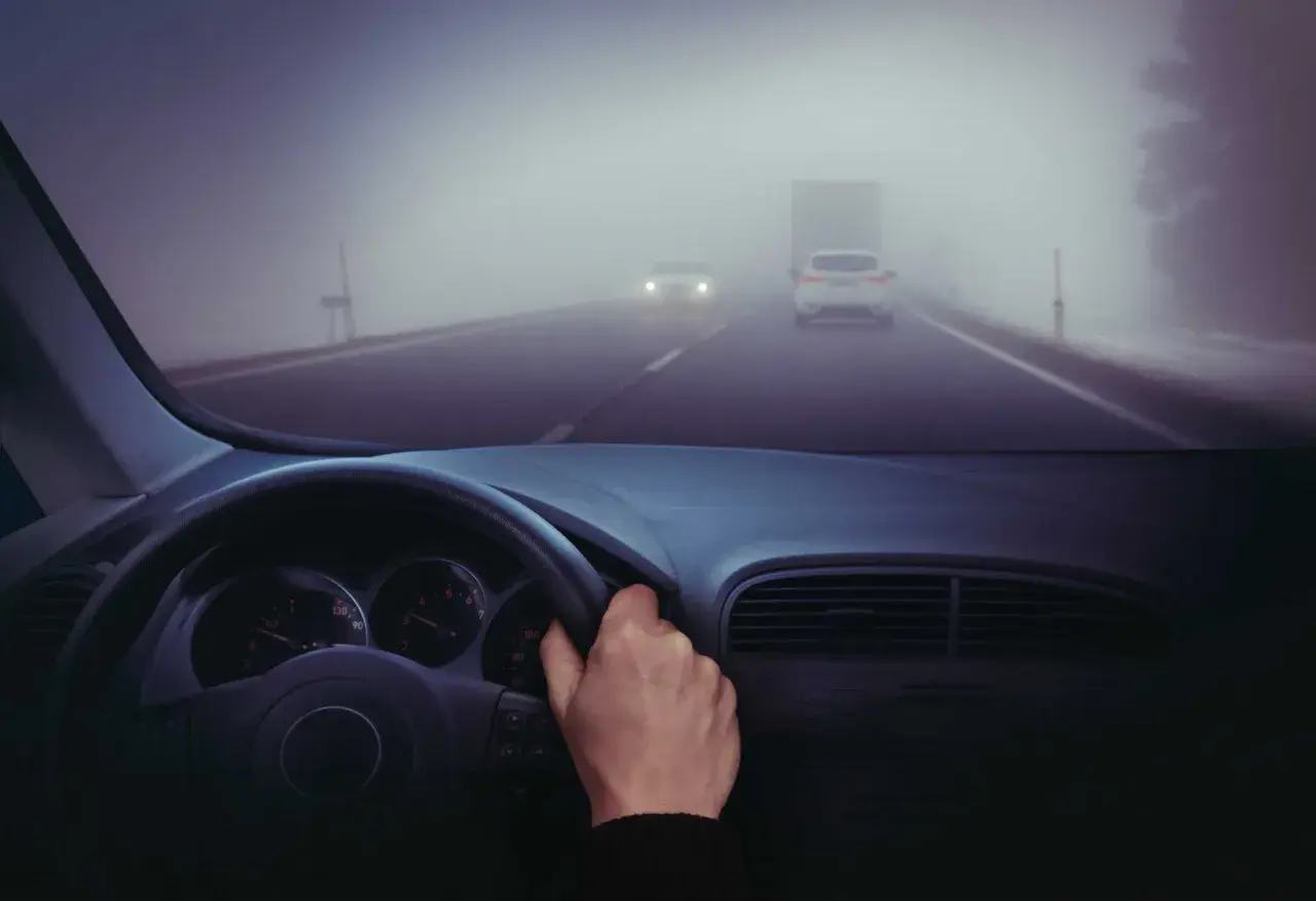 Conduciendo en carretera con poca visibilidad por niebla. Hay poca visibilidad por niebla, ¿qué debe hacer? Reducir velocidad y usar luces antiniebla.