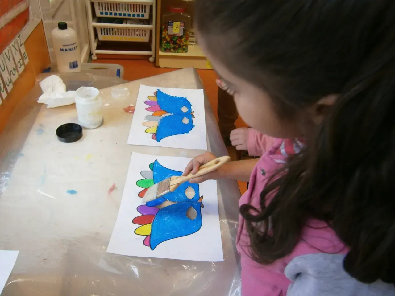Niña pinta pájaros de colores, preparándose para un día de la paz para niños.
