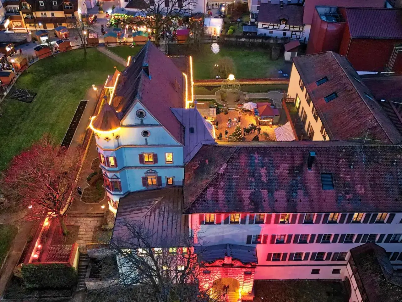 Luftaufnahme der Treuchtlinger Schlossweihnacht mit beleuchteten Buden und einem Weihnachtsbaum.