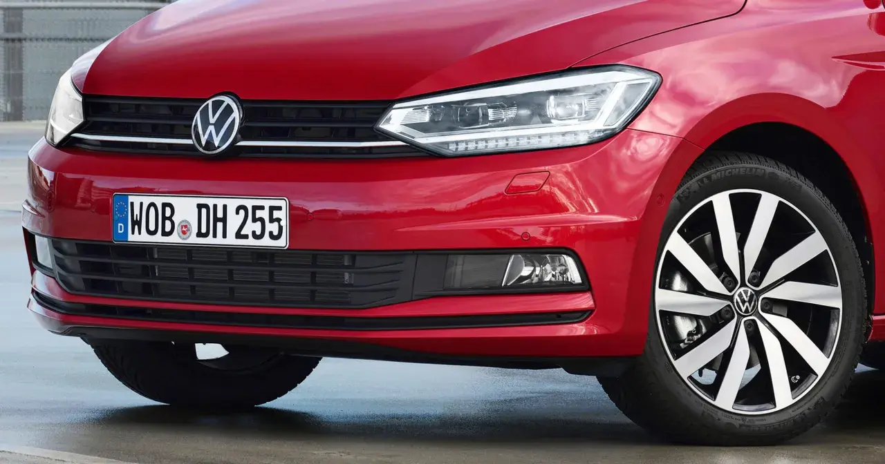 Czerwony Volkswagen Touran z błyszczącym logo i nowoczesnymi światłami.