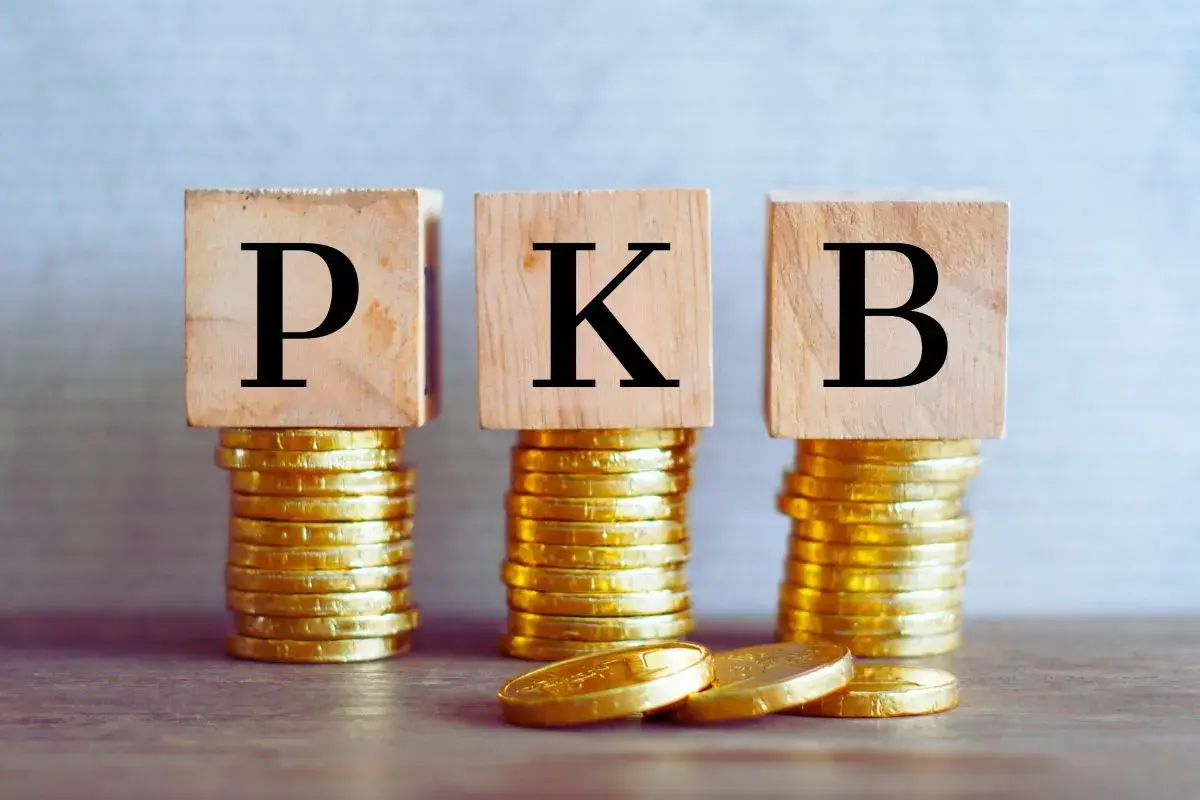 Trzy stosy złotych monet, na których stoją drewniane kostki z literami P, K, B. To symbol tego, co to PKB.
