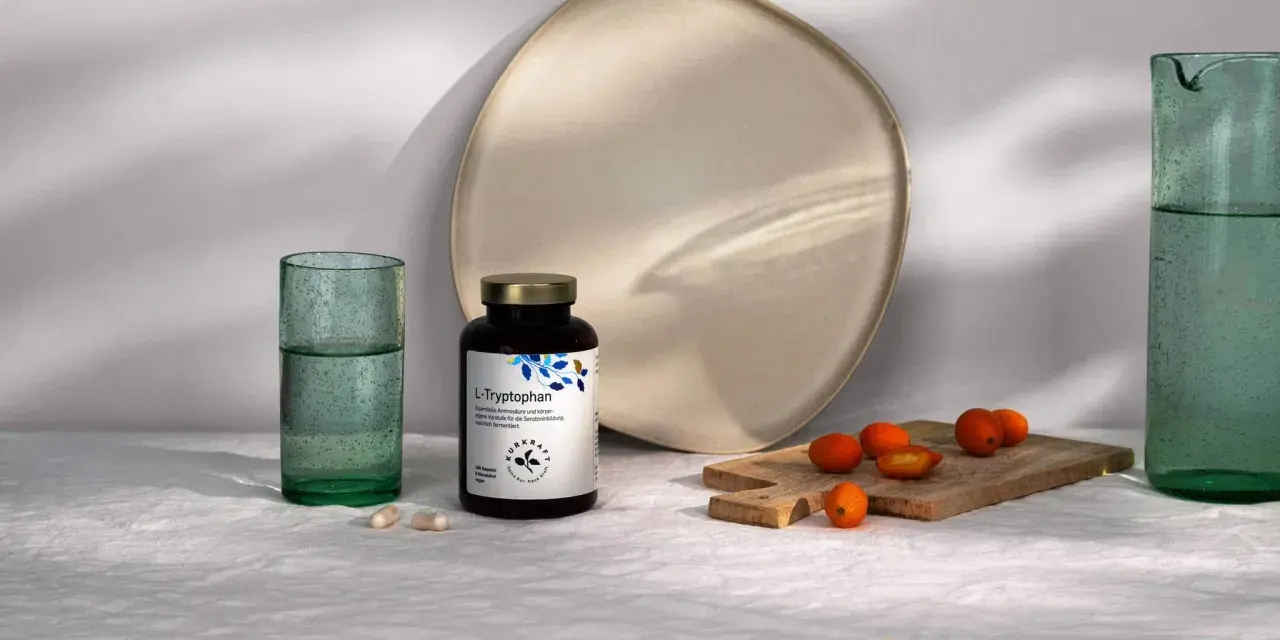Flasche L-Tryptophan, die Vorstufe für Serotonin, neben Gläsern und Kumquats.