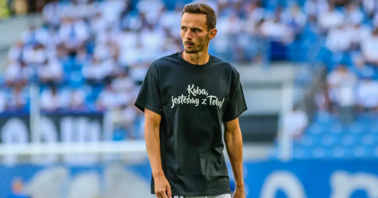 Rafał Wolski, komentator, na boisku w koszulce "Kuba, jesteśmy z Tobą!".