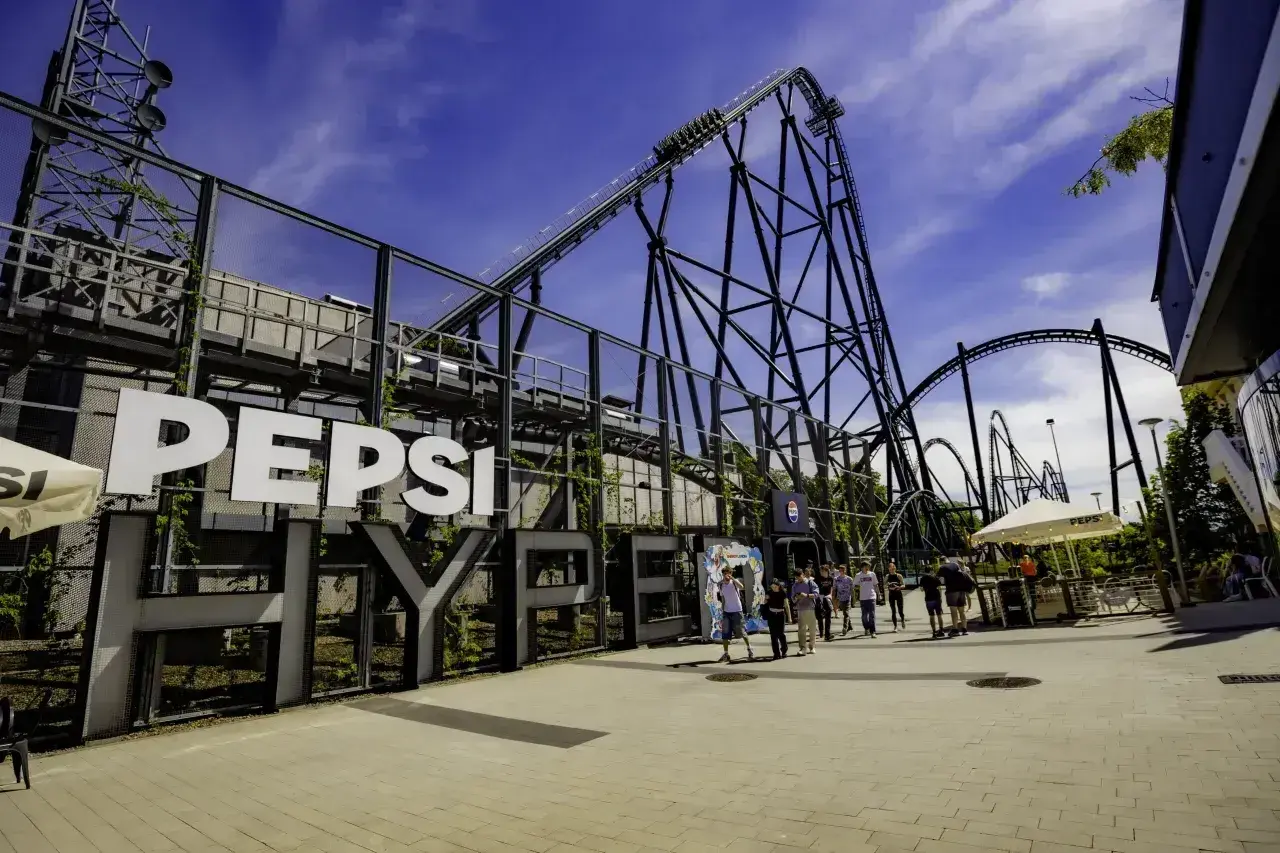Energylandia opinie: ogromna kolejka górska Pepsi z ludźmi w tle.
