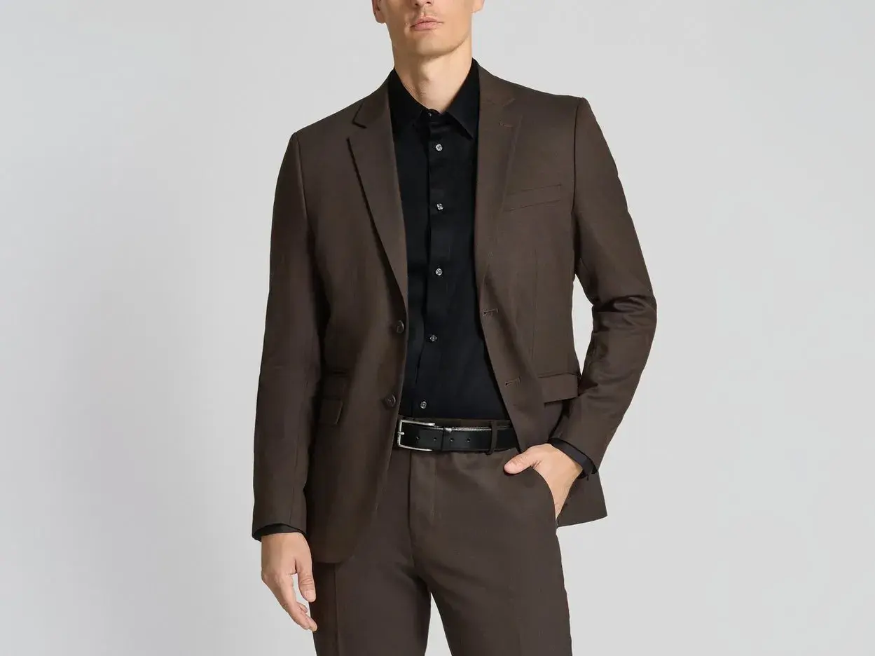 Mann im braunen Anzug mit schwarzem Hemd. So lässt sich ein schwarzes Hemd kombinieren für einen eleganten Look.