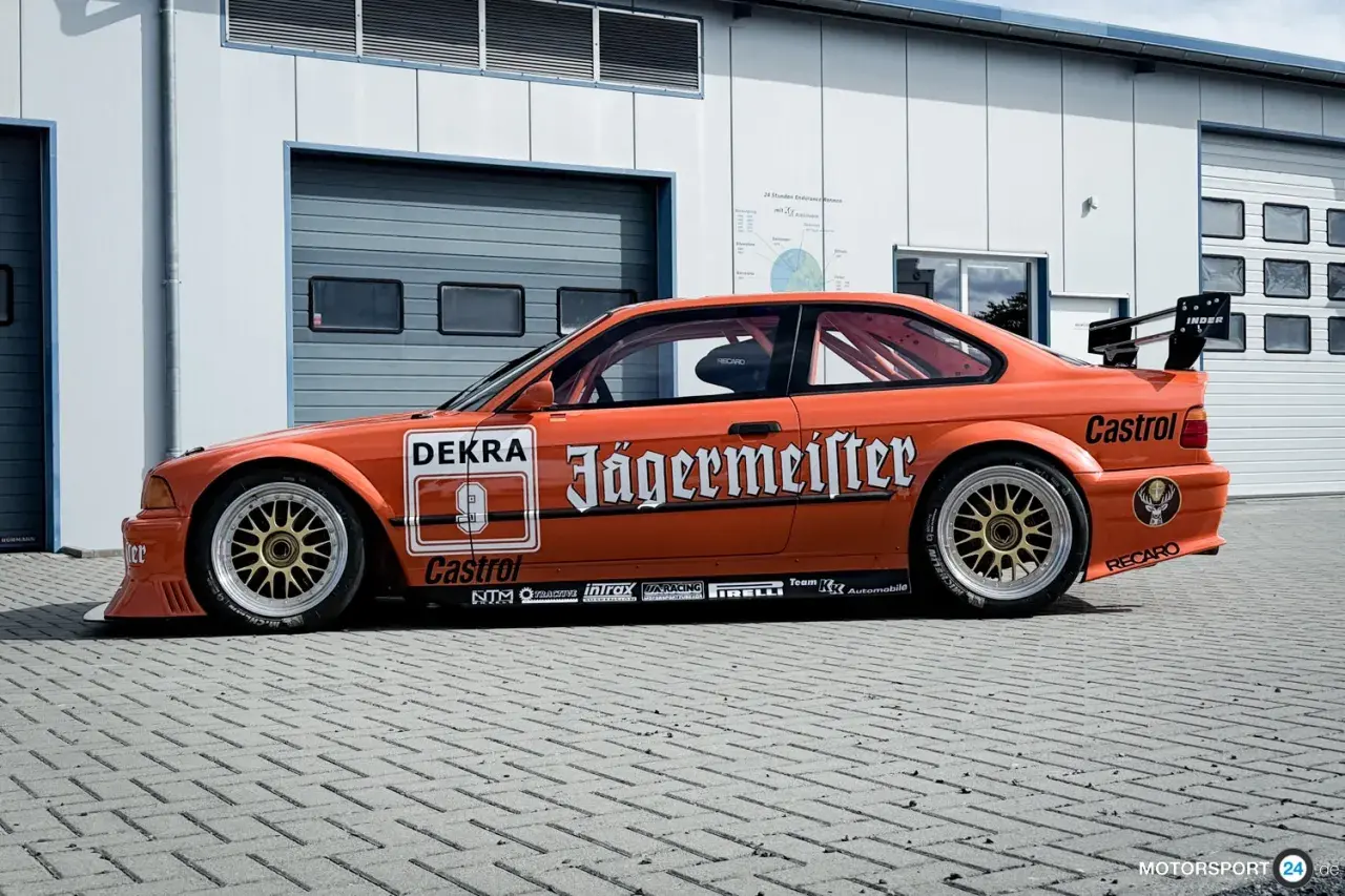 Orange BMW E36 Motorsport-Rennwagen mit Jägermeister-Lackierung und goldfarbenen Felgen.