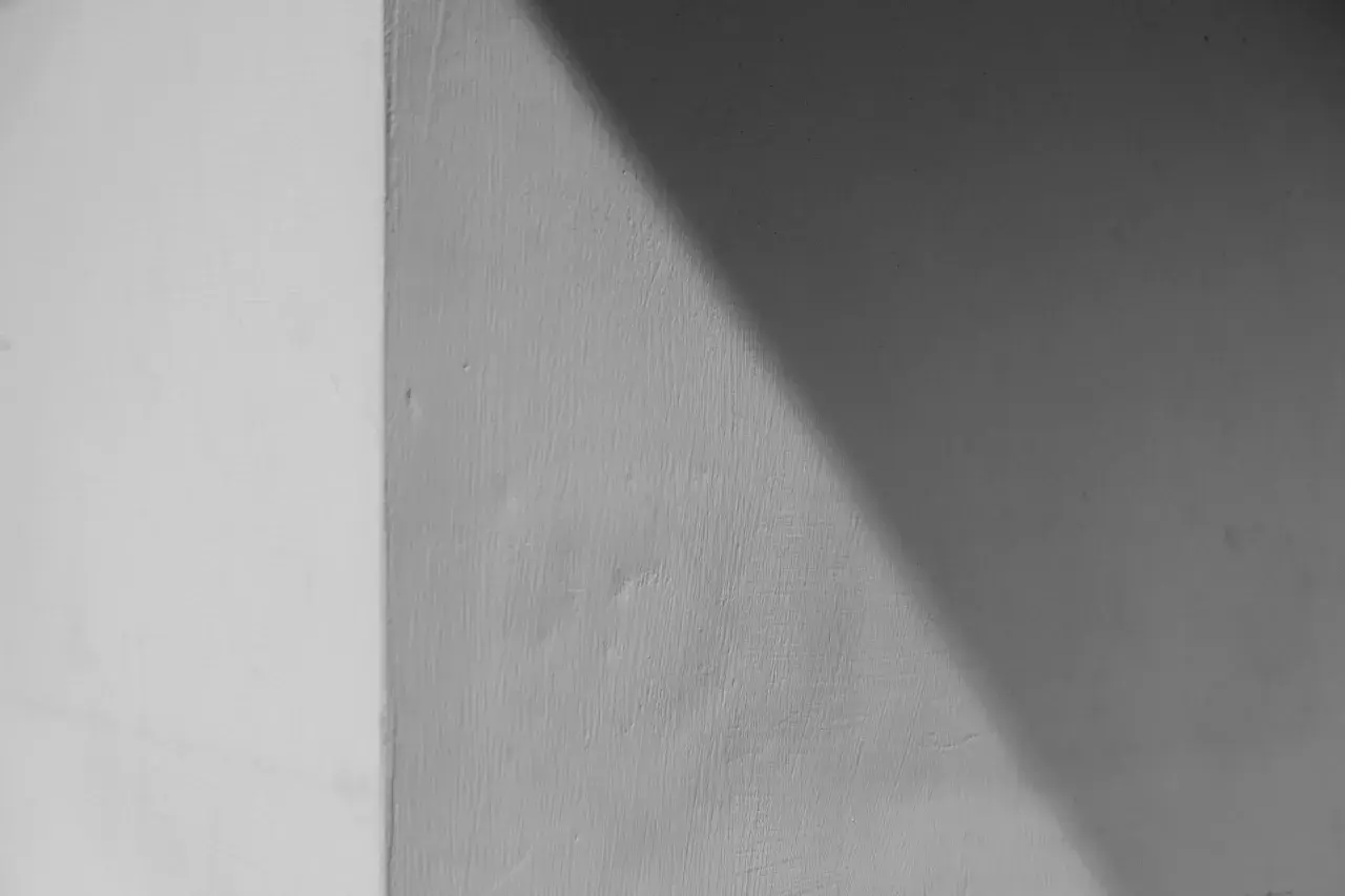Ściana z widocznym podziałem na jaśniejszą i ciemniejszą część, o chropowatej fakturze. Wygląda jakby użyto klej zamiast tynku zewnętrznego.