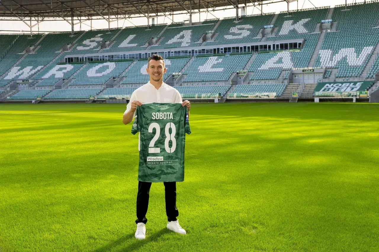 Piłkarz z koszulką "Sobota 28" na tle stadionu. To jeden z nowych śląsk wrocław transfery.
