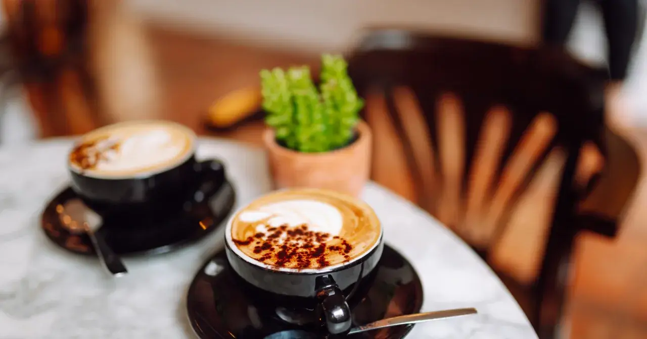 Dwie kawy latte na marmurowym stoliku. Nawet po kawie czuć senność, gdy siedzi się w przytulnej kawiarni.